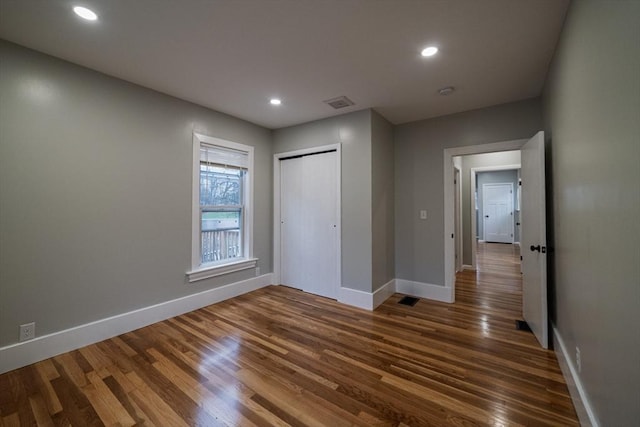 unfurnished bedroom with baseboards, dark wood-style flooring, recessed lighting, and a closet