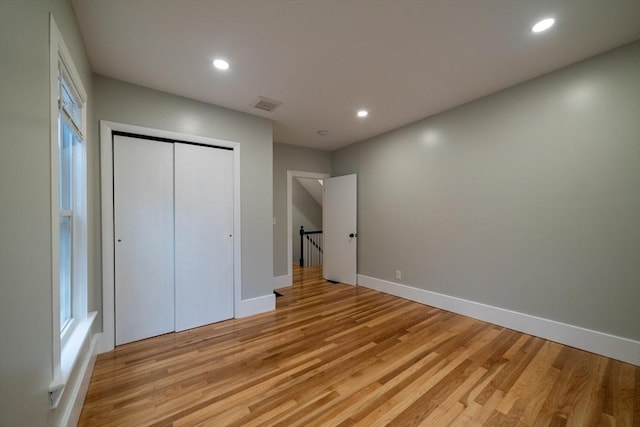 unfurnished bedroom featuring light wood-style flooring, recessed lighting, a closet, and baseboards