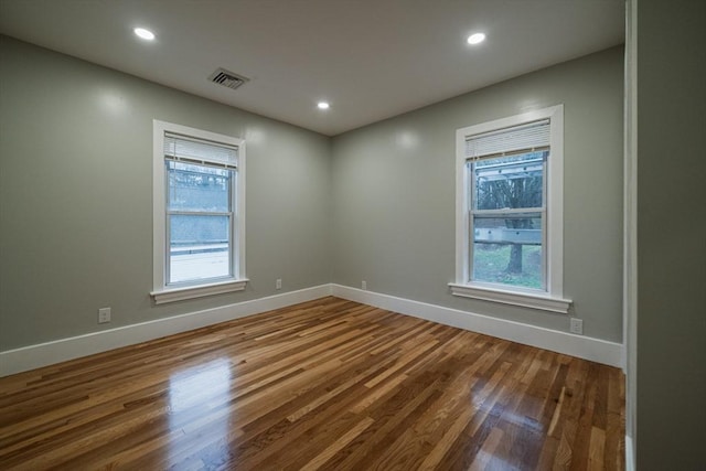 empty room featuring wood finished floors, baseboards, and recessed lighting
