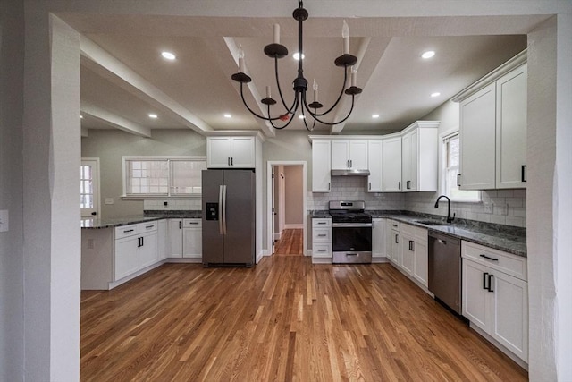 kitchen with appliances with stainless steel finishes, plenty of natural light, a chandelier, light wood-style floors, and recessed lighting