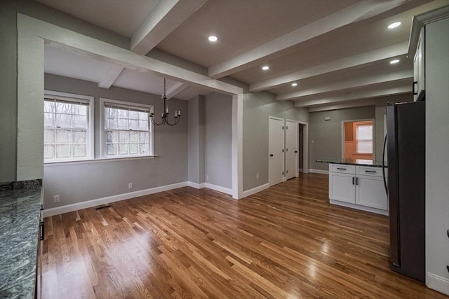 unfurnished dining area with wood finished floors, a chandelier, beam ceiling, baseboards, and recessed lighting
