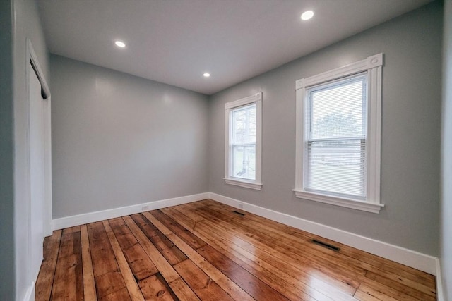 empty room featuring baseboards, hardwood / wood-style flooring, and recessed lighting