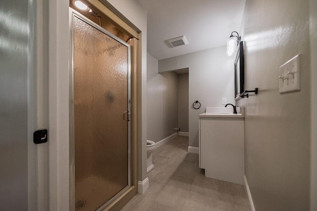 bathroom with a stall shower, vanity, baseboards, and toilet