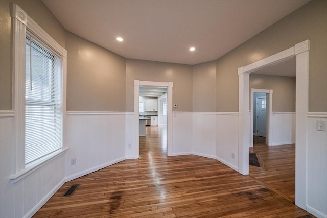 empty room with a wainscoted wall, wood finished floors, healthy amount of natural light, and recessed lighting