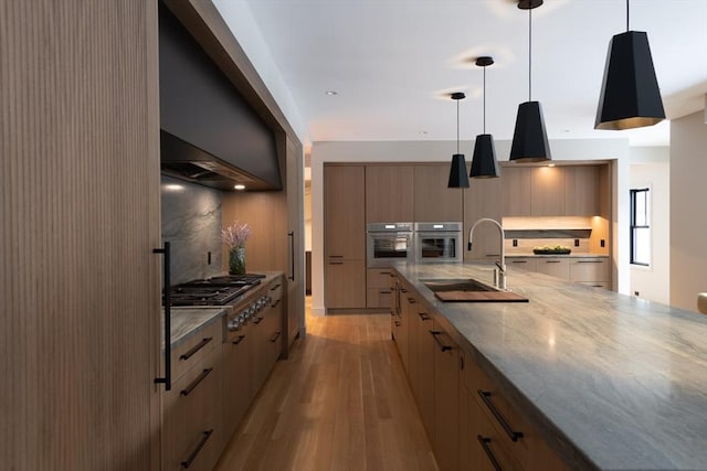 kitchen with appliances with stainless steel finishes, sink, pendant lighting, and light brown cabinets