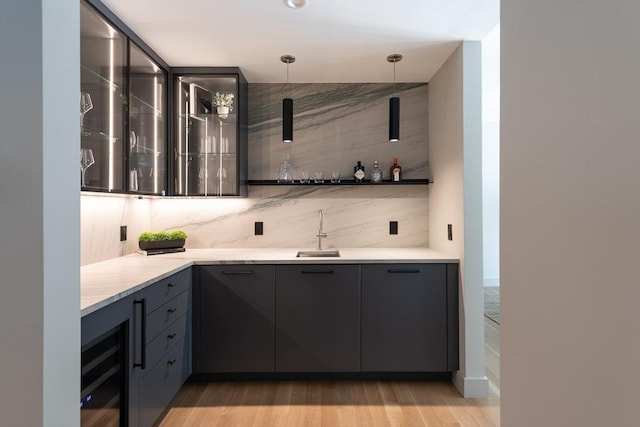 bar featuring sink, hanging light fixtures, wine cooler, light hardwood / wood-style floors, and decorative backsplash