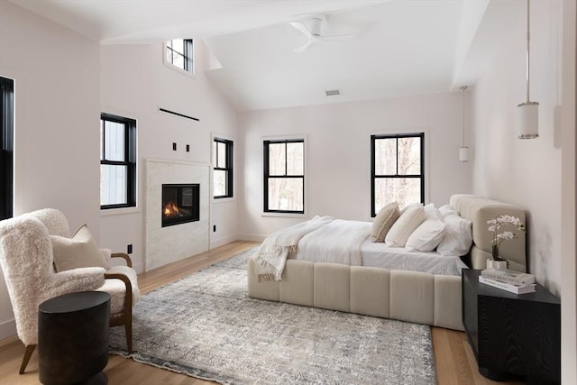 bedroom with multiple windows, high vaulted ceiling, and light hardwood / wood-style flooring