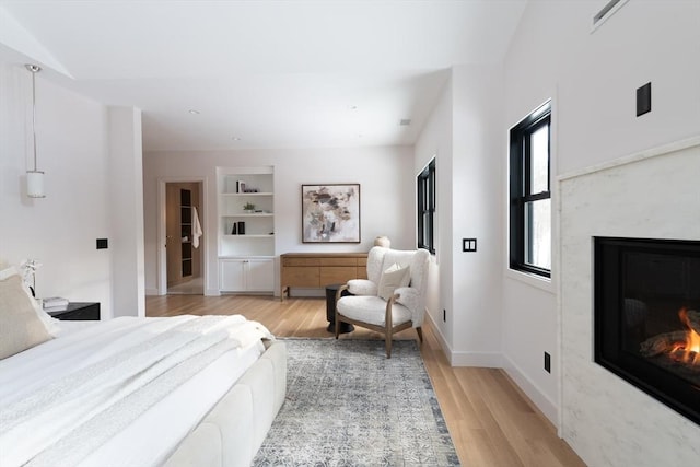 bedroom featuring a premium fireplace and light hardwood / wood-style floors