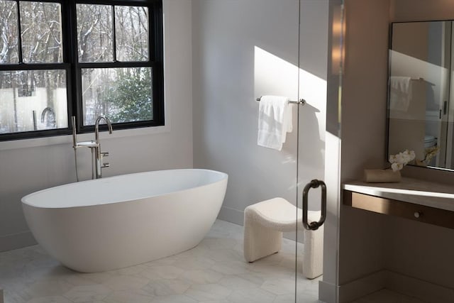 bathroom featuring a healthy amount of sunlight, vanity, and a bathtub