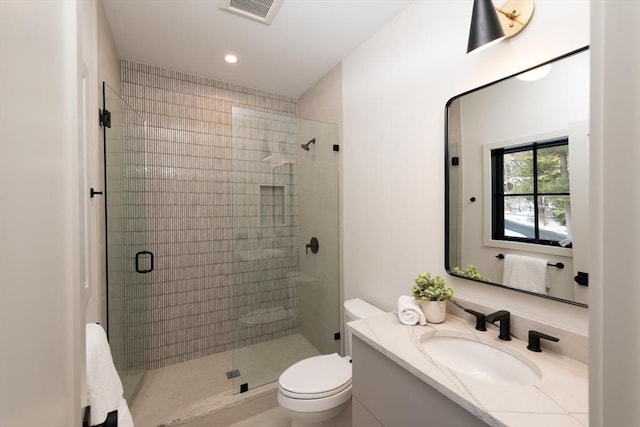 bathroom with vanity, a shower with door, and toilet