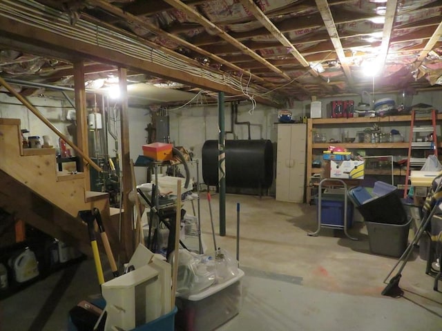 unfinished basement featuring electric panel, stairway, and heating fuel