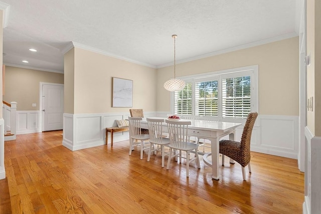 dining space with light wood finished floors, stairway, wainscoting, and ornamental molding