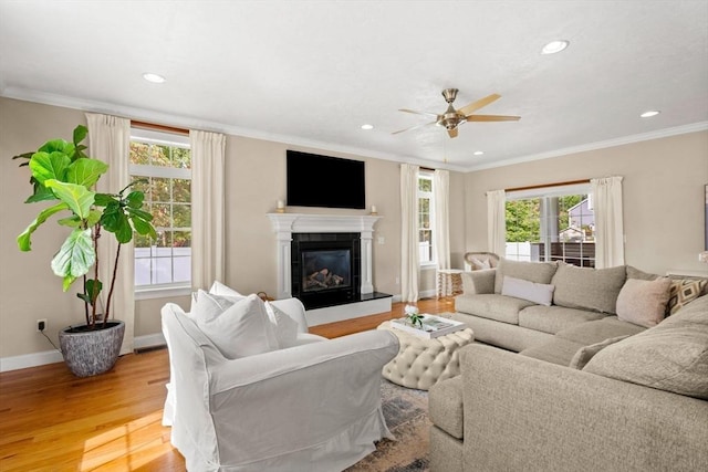 living area featuring baseboards, recessed lighting, a fireplace, ornamental molding, and light wood-type flooring