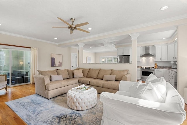 living area featuring crown molding, ceiling fan, recessed lighting, light wood-style floors, and ornate columns