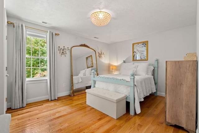 bedroom with visible vents, light wood-style flooring, and baseboards