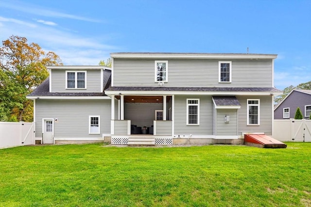 rear view of property with a gate, a fenced backyard, and a lawn