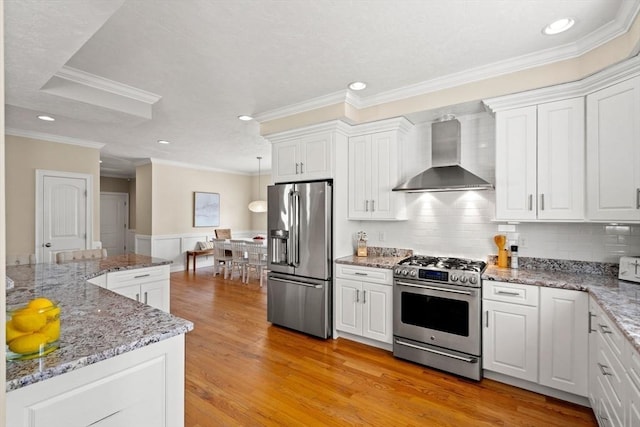 kitchen with white cabinets, wall chimney exhaust hood, and appliances with stainless steel finishes