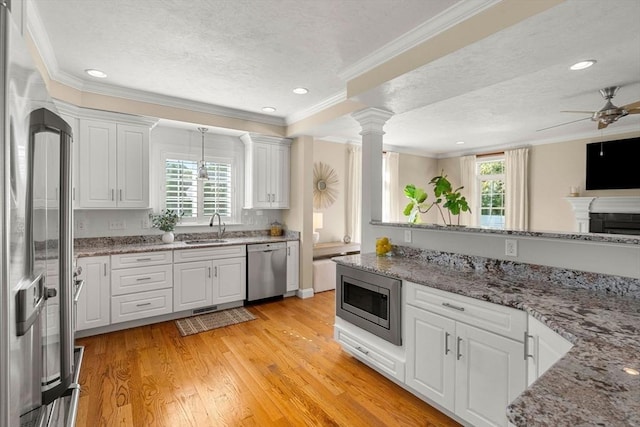 kitchen featuring a sink, stainless steel appliances, plenty of natural light, and white cabinetry