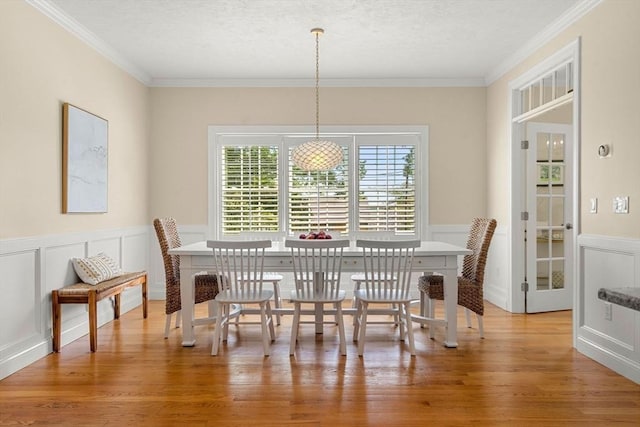 dining area with light wood finished floors, a textured ceiling, and crown molding