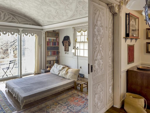 bedroom featuring hardwood / wood-style floors, ornamental molding, lofted ceiling, and access to outside