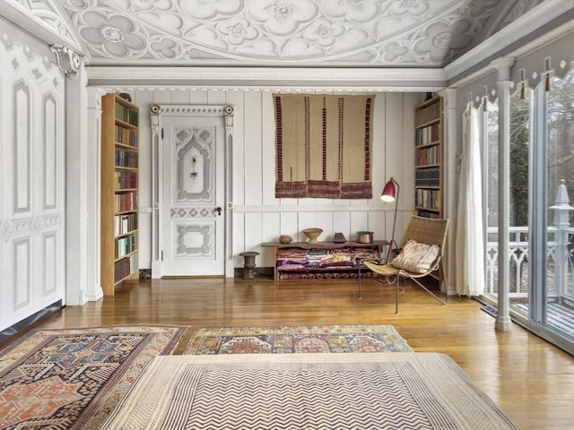 living area with ornamental molding, decorative columns, and hardwood / wood-style floors