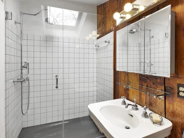 bathroom featuring sink, a shower with shower door, and wooden walls