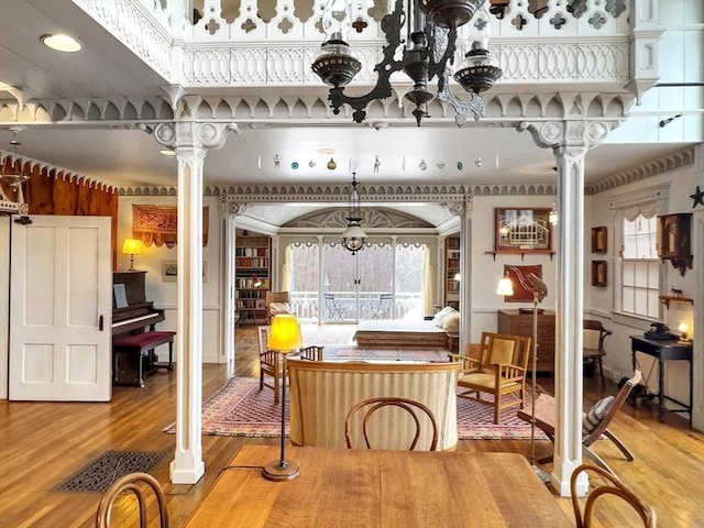 dining space featuring wood-type flooring, decorative columns, and plenty of natural light