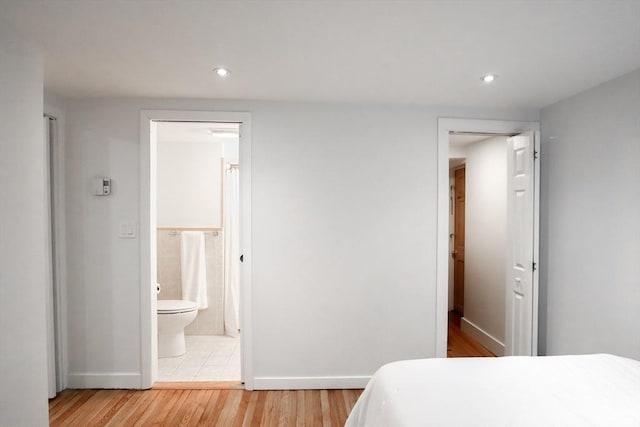 bedroom with ensuite bathroom and light hardwood / wood-style floors