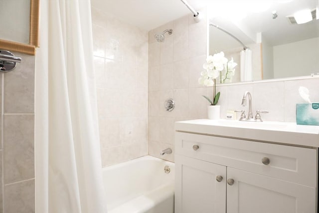 bathroom featuring vanity, backsplash, shower / bathtub combination with curtain, and tile walls