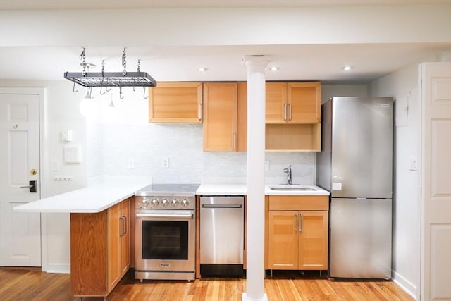 kitchen featuring sink, light wood-type flooring, appliances with stainless steel finishes, tasteful backsplash, and kitchen peninsula