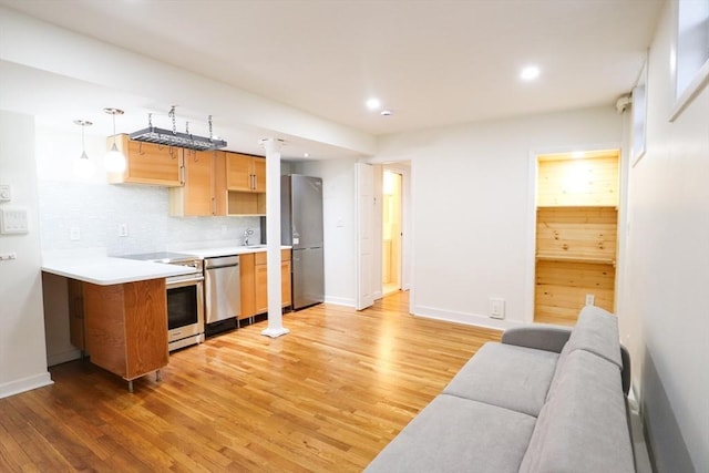 kitchen with pendant lighting, backsplash, hardwood / wood-style flooring, and appliances with stainless steel finishes