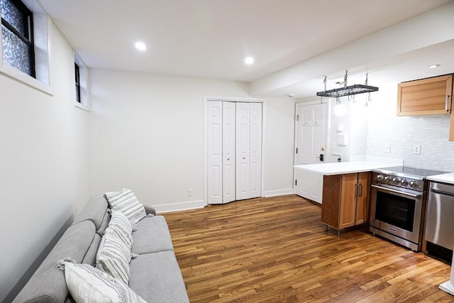 kitchen with decorative backsplash, dark hardwood / wood-style flooring, kitchen peninsula, and stainless steel appliances