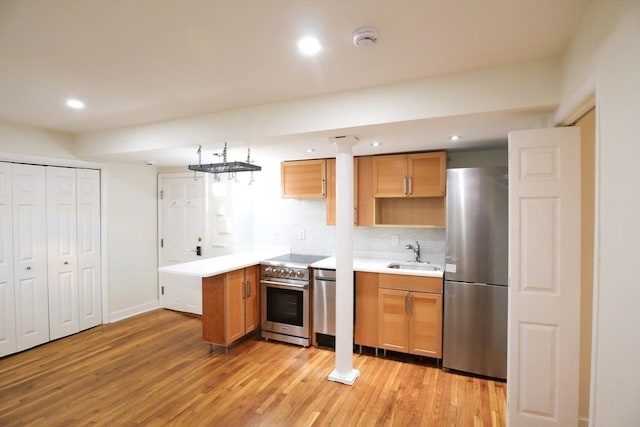 kitchen featuring backsplash, sink, light wood-type flooring, kitchen peninsula, and stainless steel appliances