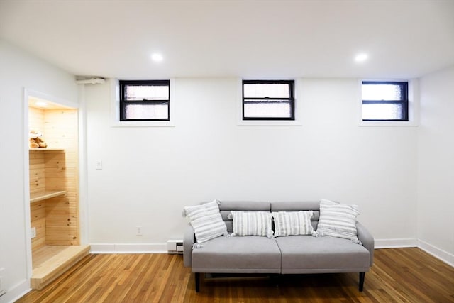 living area featuring baseboard heating and hardwood / wood-style flooring