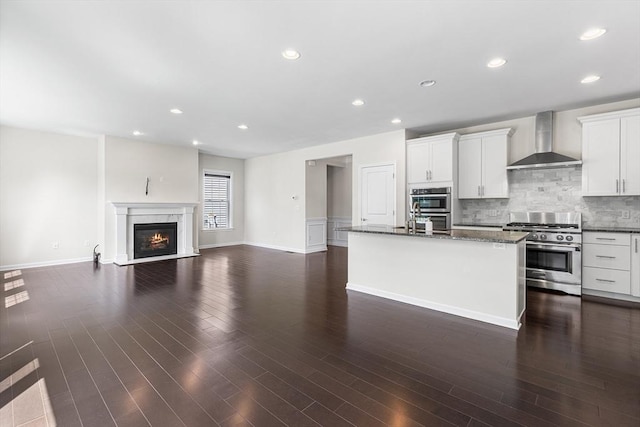 184 Stonehaven Dr, Weymouth, MA 02190 - kitchen featuring wall chimney range hood, stainless steel appliances, white cabinetry, a kitchen island with sink, and backsplash