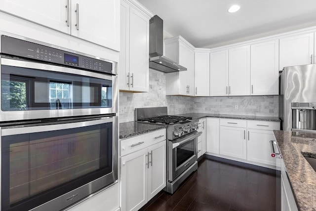 184 Stonehaven Dr, Weymouth, MA 02190 - kitchen with stainless steel appliances, wall chimney range hood, white cabinetry, dark stone counters, and recessed lighting