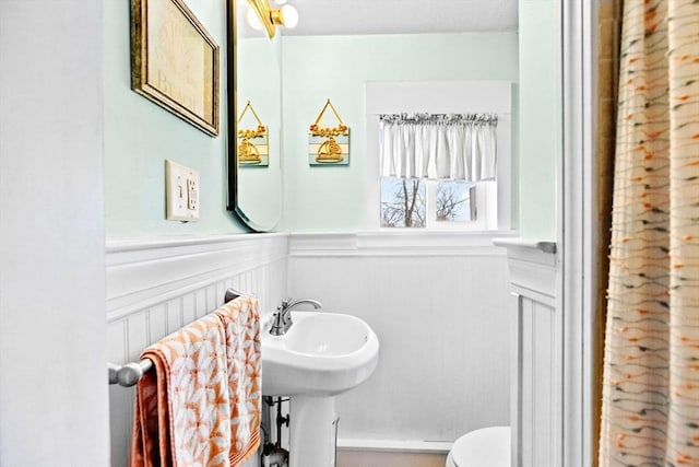 half bath with wainscoting and toilet