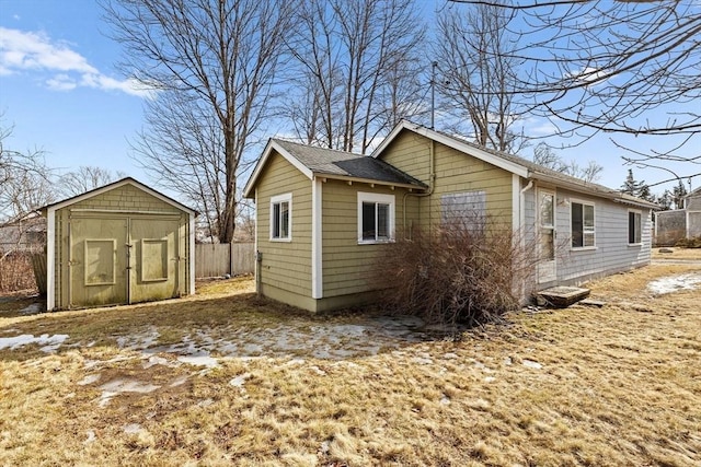 view of side of home featuring a storage shed, fence, and an outdoor structure