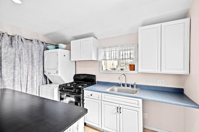 kitchen featuring stacked washer and dryer, a sink, white cabinetry, gas stove, and dark countertops