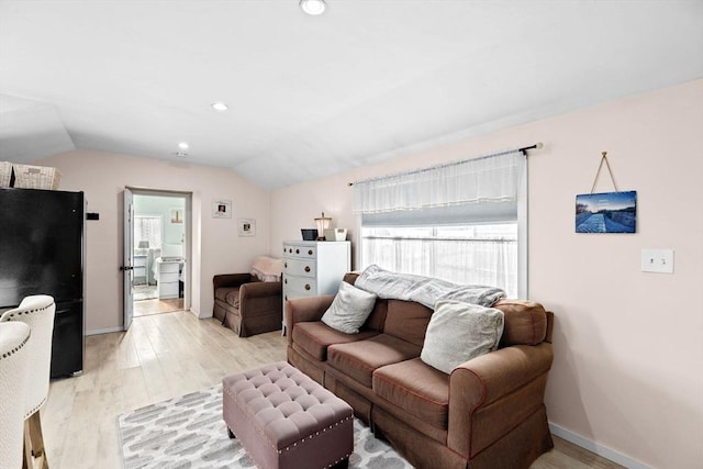 living room featuring lofted ceiling, light wood-style floors, baseboards, and recessed lighting