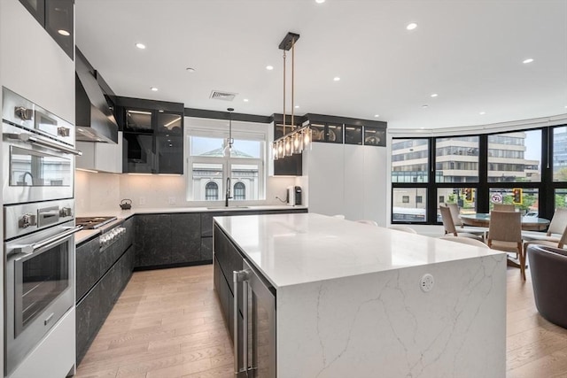 69 Walnut St Unit 4, Brookline, MA 02445 - kitchen with dark cabinetry, light wood finished floors, modern cabinets, a center island, and recessed lighting