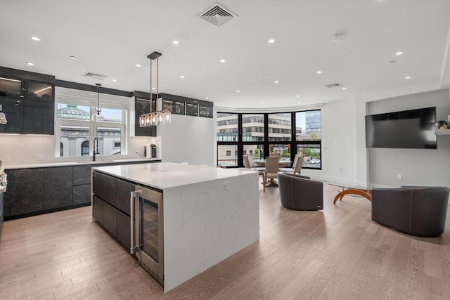 69 Walnut St Unit 4, Brookline, MA 02445 - kitchen with beverage cooler, modern cabinets, light wood-style flooring, a kitchen island, and hanging light fixtures