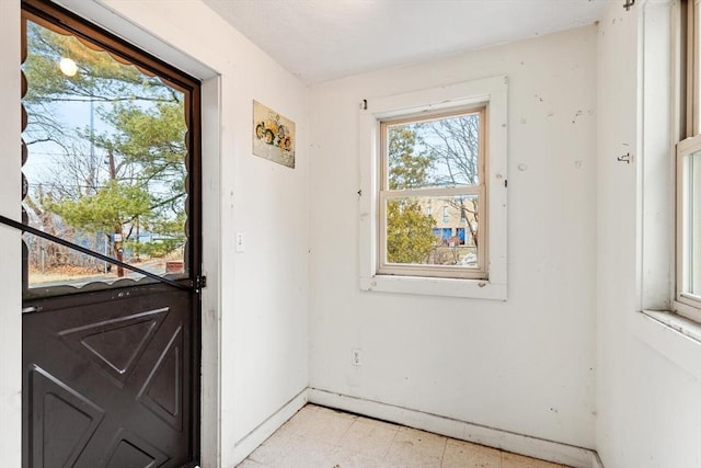 doorway to outside featuring baseboards and light floors