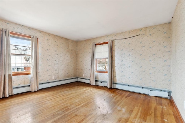 spare room featuring a baseboard radiator, hardwood / wood-style flooring, and wallpapered walls