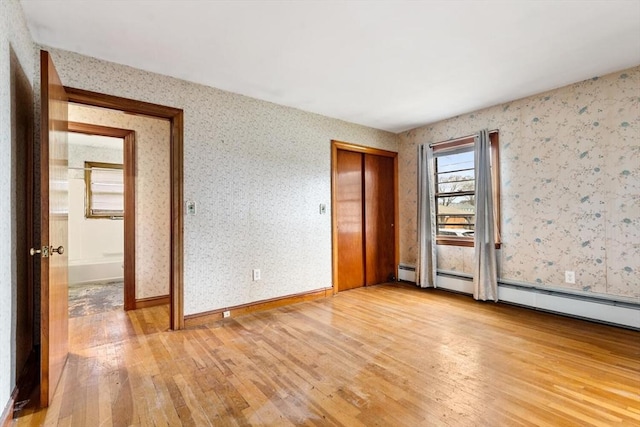 empty room with baseboards, light wood finished floors, baseboard heating, and wallpapered walls