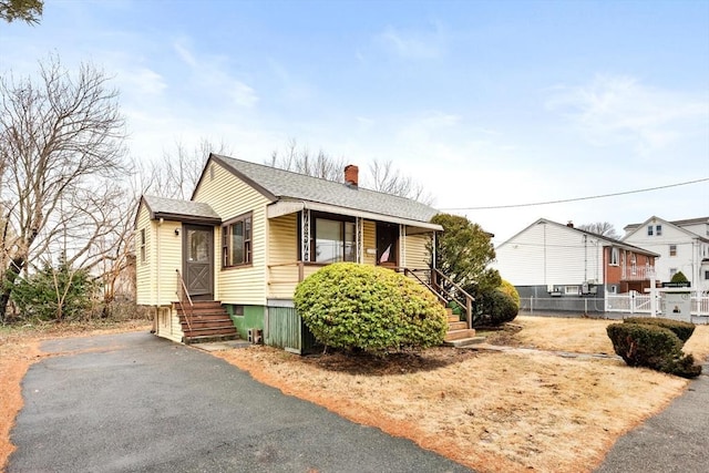 view of front of property featuring roof with shingles, a chimney, and fence