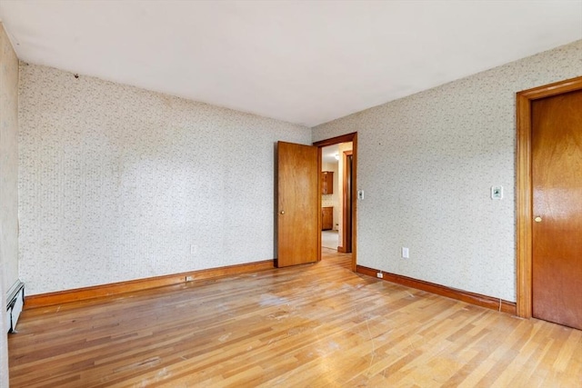 empty room with wallpapered walls, baseboards, and wood finished floors