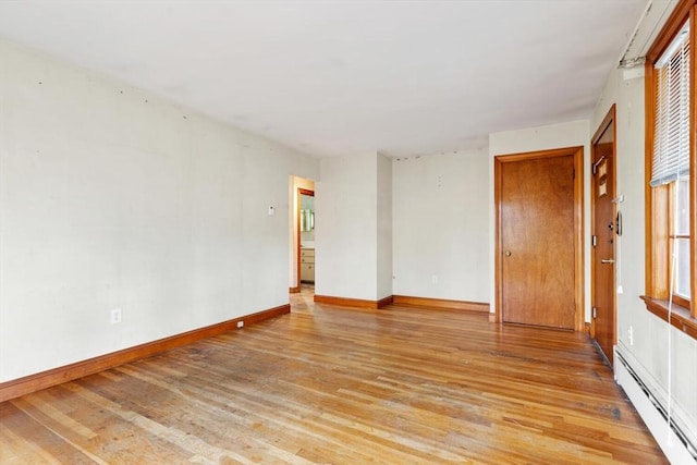 unfurnished room featuring light wood-type flooring, a baseboard radiator, and baseboards