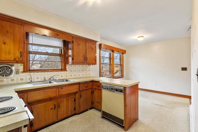 kitchen featuring a peninsula, a sink, light countertops, dishwasher, and light floors