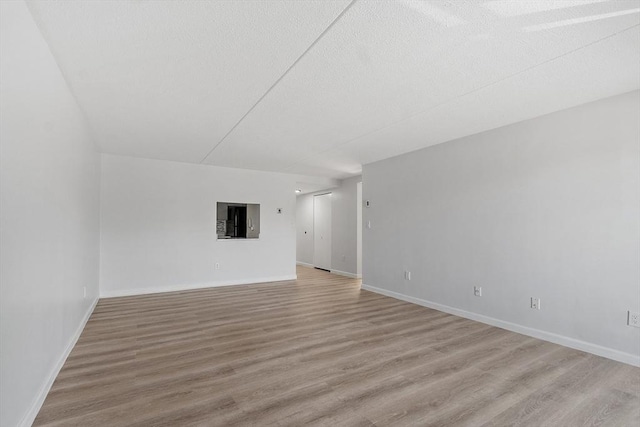empty room with baseboards and light wood-type flooring